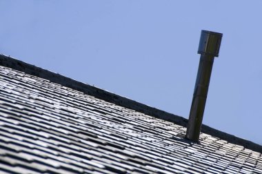 Çatı yapısı açık mavi gökyüzüne karşı bacayı gösteriyor