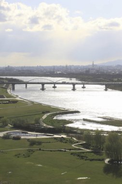 Gün ışığı, uzak şehir siluetiyle geniş bir nehrin üzerinde parlıyor.