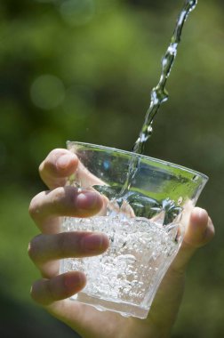 close-up view of person holding glass of water in hand outdoors                     clipart