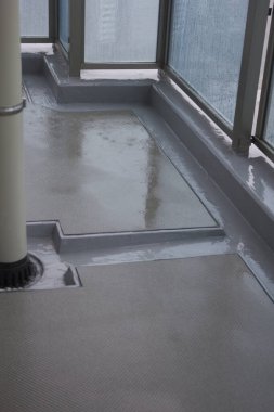 Islak balkon, cam panellerden şehir binalarını yansıtıyor.