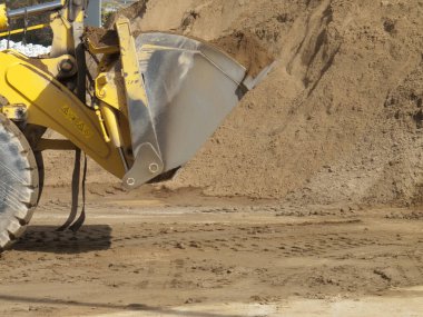 Sarı tekerlek yükleyici kovanın kumu kepçelediği yakın çekim görüntüsü