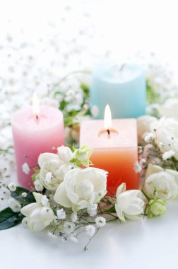 Yakıcı mumların ve parlak arkaplanda güzel beyaz çiçeklerin yakın plan görüntüsü                                   