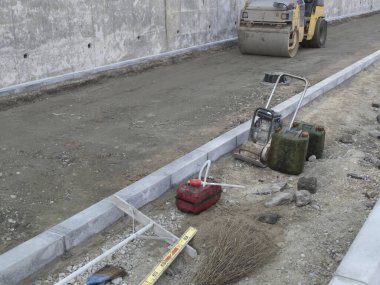 Sıkıştırıcı makine süpürge araçlarını gösteren yol inşaatı alanı çakıl yüzeyi
