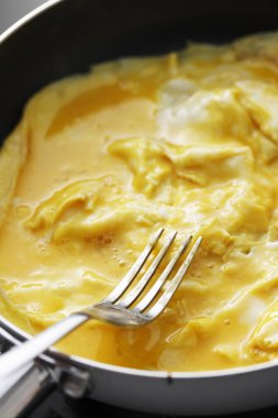 Tavada yumurta ve çatalın yakın görüntüsü. 