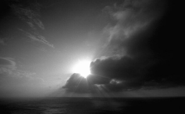 beautiful view of sea and sun with clouds in sky, black and white 