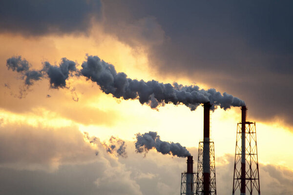 industrial factory with pipes against sunset sky       