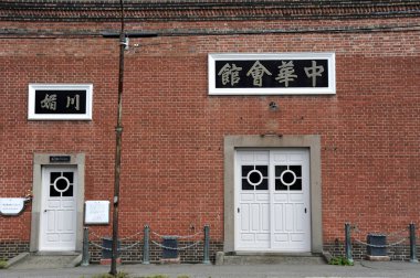 Beyaz kapılar ve Çince tabelalar içeren tarihi kırmızı tuğla bina