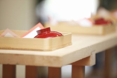 Tahta tepsilerde kırmızı tabaklar olan ahşap bir masa.