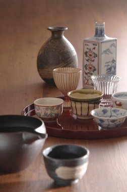 Ahşap masada duran çeşitli seramik bardaklar ve vazolar.
