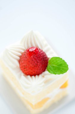 Kırmızı çilekle süslenmiş lezzetli kremalı pasta.