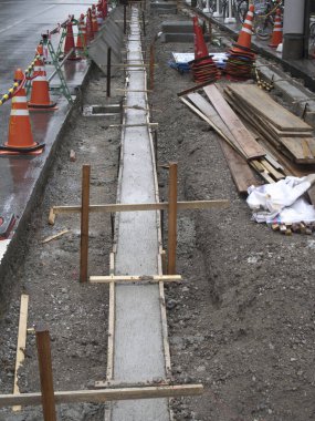Islak şehir caddesi inşaat alanı boyunca taze beton kaldırım oluşumu