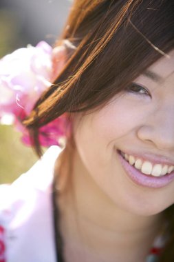 Saçında pembe çiçek olan Asyalı kadının portresini kapat.  