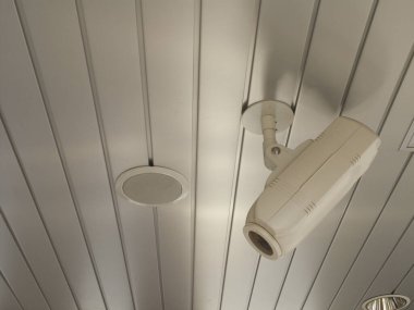 Tavana monte edilmiş kamera ve hoparlör beyaz panelde.