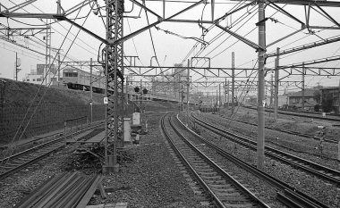 Japon demiryollarından geçen siyah beyaz tren görüntüsü.