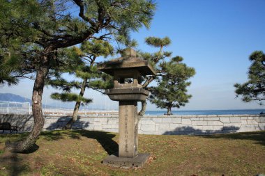 Beams of hot summer sun highlight the fine, aged details of the park's statue.	