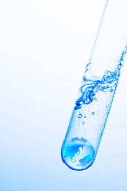 Beyaz zemin üzerinde mavi sıvı bulunan laboratuvar test tüpünün yakın görüntüsü                  