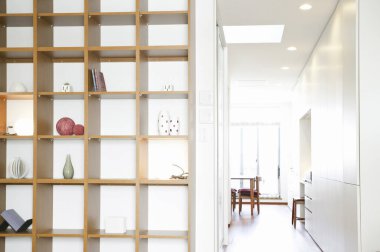 Modern ahşap raf ünitesi parlak koridorun yanında dekoratif nesneler sergiliyor.