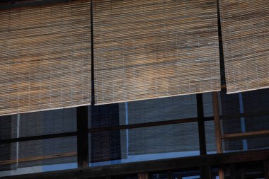 Bambu panjurları büyük cam pencerelerde asılı.