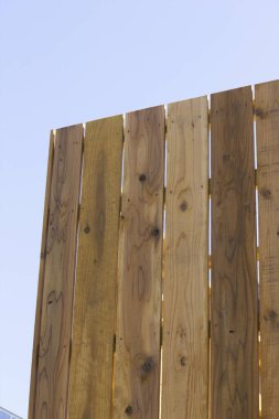 Açık mavi gökyüzü arka planına karşı dikey ahşap çit panelleri