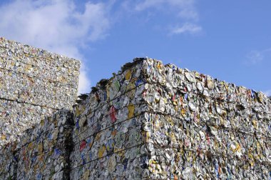 Mavi gökyüzünün altında ezilmiş metal kutulardan oluşan büyük sıkıştırılmış küpler.