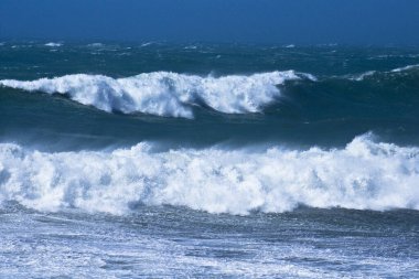 Denizdeki dalgaların gündüz görüntüsü. Denizin üzerindeki mavi gökyüzü