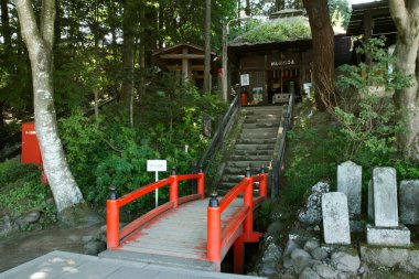 Geleneksel Japon tapınağı girişine doğru giden kırmızı tahta köprü.