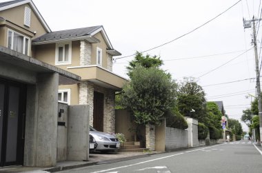 Banliyö evleri ve yeşil ağaçları olan güzel bir sokak manzarası.