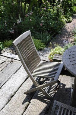 Tahta masa ve sandalye bahçede terasta.