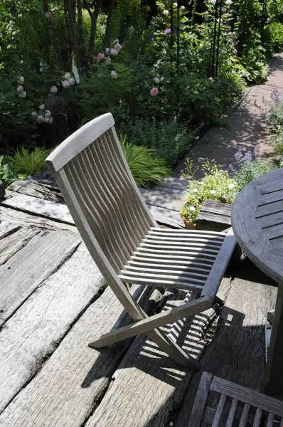 Tahta masa ve sandalye bahçede terasta.