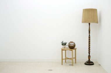 Küçük yuvarlak vazonun yanında ahşap masa lambası