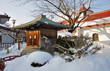 Geleneksel Japon tapınağını ve çevreleyen bahçe bitkilerini kaplayan kar