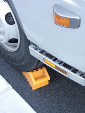 Araç tekerleği asfaltta sarı tıkaçla korunuyor.