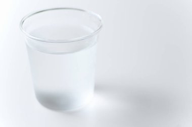Beyaz arkaplanda plastik bardakta saf su