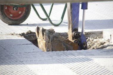 Beton yüzey, çukur kazma ekipmanı gösteriyor.