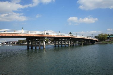 Sakin mavi nehir suyu boyunca uzanan uzun beton köprü