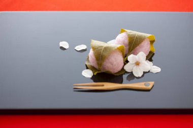 Japon Mochi. Lezzetli yuvarlak tatlılar çiçekler, taç yaprakları ve ahşap çatalla servis edilir. 