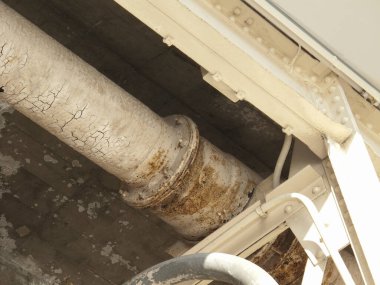 Yakın çekimde yıpranmış endüstriyel boru, soyulmuş boya ve pas lekeleri görülüyor.