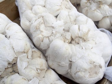 Şehirdeki bir markette, beyaz poşetlerdeki olgun sarımsağın yakın plan görüntüsü.