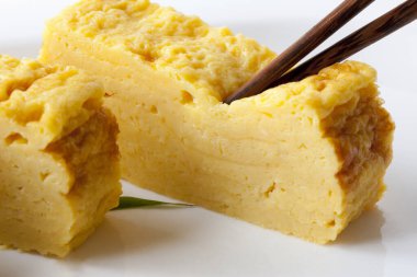 Beyaz tabakta dilimlenmiş sarı Japon omleti.