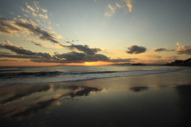 Denizin üzerinde gün doğumu Güzel bir plajla.