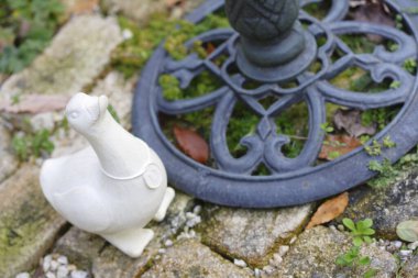 Beyaz seramik bir ördek heykeli ve siyah dövmeli yuvarlak bir süsleme. 