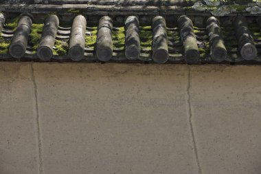 Yıpranmış kil çatı kiremitleri desenli bej duvarın üzerinde duruyor