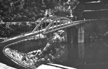 Nehrin üzerindeki köprünün manzaralı kış dağlarındaki siyah beyaz fotoğrafı   