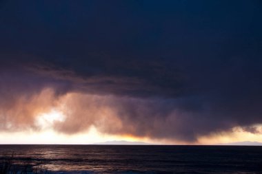 Gün batımında deniz üzerinde turuncu gökyüzü manzarası 