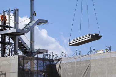 İnşaat alanında vinçle mavi gökyüzüne tutulan beton kiriş