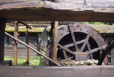 Kırsal ahşap binanın yanında dönen eski ahşap su çarkı.