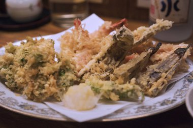 Soslu kızarmış deniz ürünleri ve beyaz tabakta limon. 