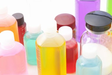 Işık arkaplanındaki renkli plastik sıvı şişelerinin yakın plan görüntüsü       