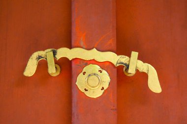 Altın kapı kolu kırmızı ahşap kapıda.