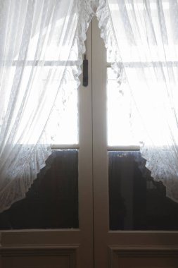 Perdelerin arasından parlayan ışık ahşap kapıları kapatıyor.